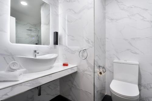 a white bathroom with a sink and a toilet at Vegas Resort in St. Julianʼs