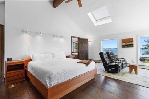 a bedroom with a bed and two chairs in it at Clark Point Cottage, ocean access, panoramic views in Clark Island