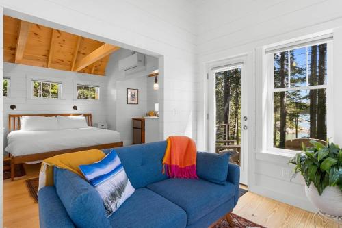 a bedroom with a blue couch and a bed at Lindquist Cottage | Waterfront Studio with King Bed in Clark Island