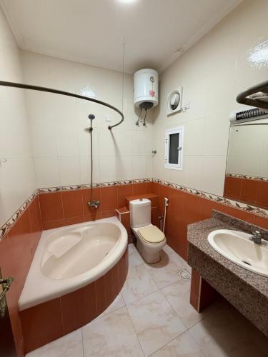 a bathroom with a tub and a toilet and a sink at Al Barka Palace Hotel in Ma‘ābīlah