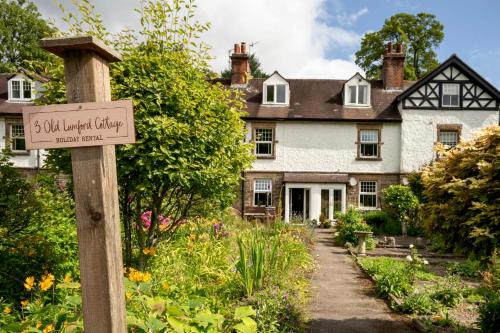 a sign in front of a house with a garden at Old Lumford Cottage, Bakewell - Picturesque Riverside Property in Bakewell