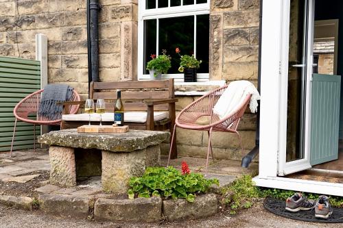 a patio with a table and chairs and a bottle of wine at Old Lumford Cottage, Bakewell - Picturesque Riverside Property in Bakewell
