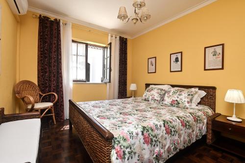 a bedroom with a bed and a chair and a window at Cottage Sete Mares in Colares