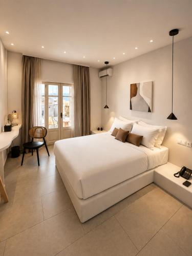 a bedroom with a large white bed and a desk at Domotel Kea in Koundouros