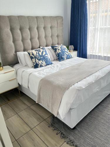 a bedroom with a large white bed with blue pillows at House 22 on Alice in Centurion