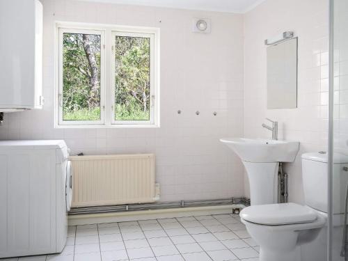a white bathroom with a toilet and a sink at 12 person holiday home in BÅSTAD-By Traum in Båstad