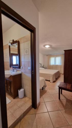 a room with a bathroom with a sink and a bed at Casa Manchia in Loiri