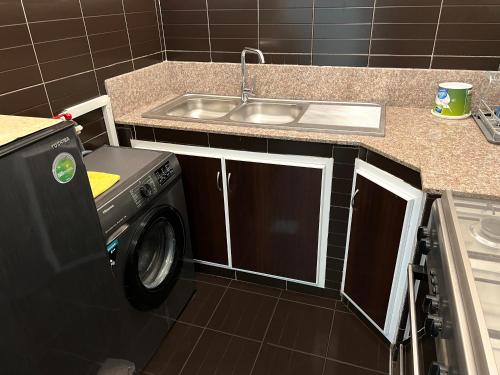 a kitchen with a sink and a washing machine at Stylish 2BR Escape Near Muscat City Centre in Mawāliḩ