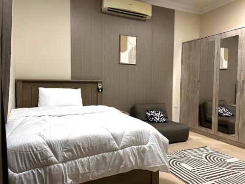 a bedroom with a white bed and a chair at Stylish 2BR Escape Near Muscat City Centre in Mawāliḩ