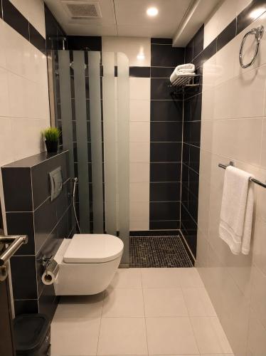 a bathroom with a toilet and a shower with black tiles at Smart Gate Hotel Apartments سمارت غيت للشقق الفندقية in Jazan