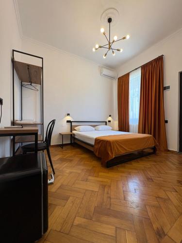 a bedroom with a bed and a desk and a chair at Polifonia Inn Borjomi in Borjomi