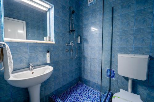 a blue tiled bathroom with a sink and a shower at Hotel Callatis in Neptun