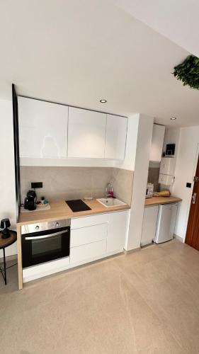 a kitchen with white cabinets and a black oven at Studio cosy Plage à pied Parking in La Grande Motte