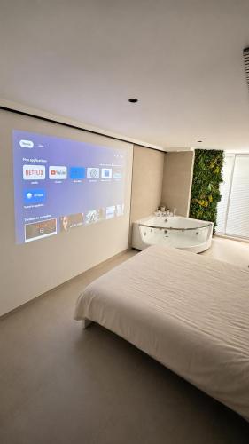 a bedroom with a large screen with a bed and a sink at Studio cosy Plage à pied Parking in La Grande Motte