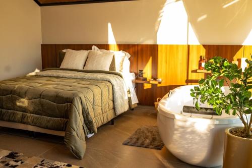 a bedroom with a bed and a bath tub at Encosta do Café - Chalé Oliveira in Itati