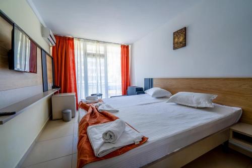 a bedroom with a bed with white sheets and a window at Hotel Recif in Neptun