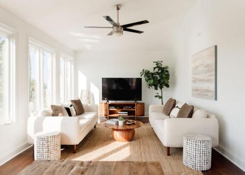 a living room with two white couches and a flat screen tv at Marshfront 5BD Oasis Pool Yard & Steps to Beach in Folly Beach