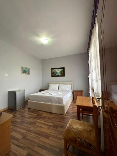 a bedroom with a white bed and a table at Hotel Klajdi in Peshkopi