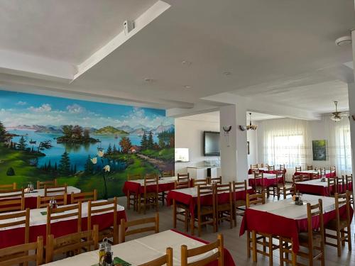 a restaurant with tables and chairs and a large mural at Hotel Klajdi in Peshkopi