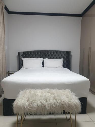 a bed with a black headboard and a white blanket at 2Bedroom Luxury hotel apartment Fourways in Johannesburg