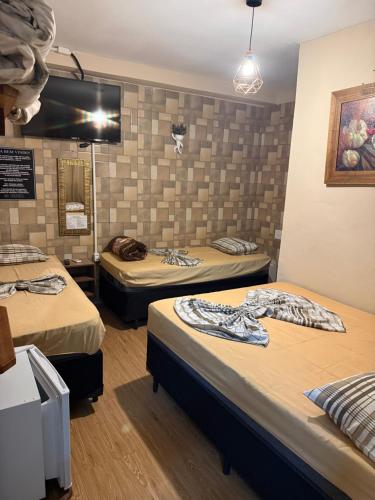 a room with three beds and a mirror at Pousada Castro in Aparecida