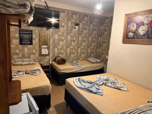 a room with two beds and a tv on the wall at Pousada Castro in Aparecida
