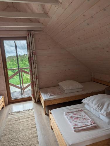a bedroom with two beds in a wooden cabin at Sielski Domek Na Wzgórzu in Sulęczyno