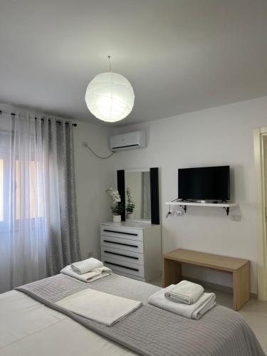 a white bedroom with a bed and a television at Kloa Apartments in Orikum