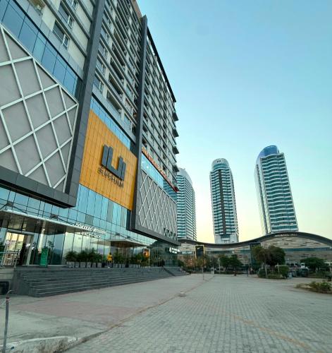 a large building with tall buildings in a city at Designer One Bedroom Apartment With Balcony & Mountain Views Opposite Centaurus Mall ISB in Islamabad