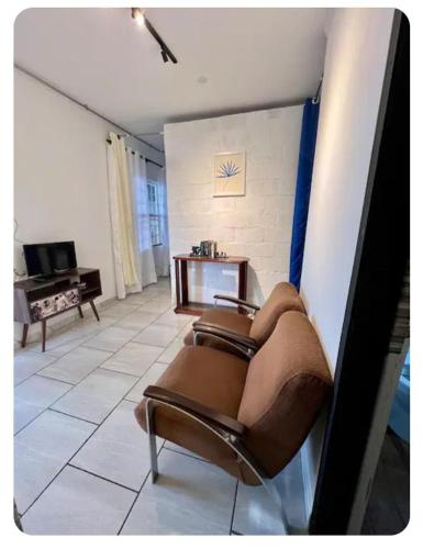 a living room with two brown chairs and a tv at Chácara Lobos in Sorocaba
