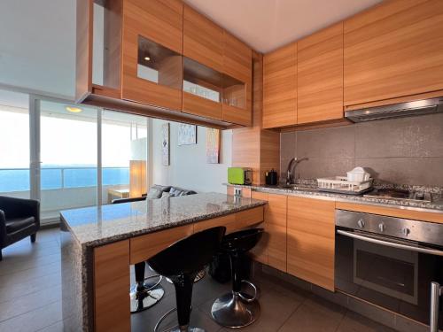 a kitchen with wooden cabinets and a counter with bar stools at Oceana Suites Costa Montemar in Concón