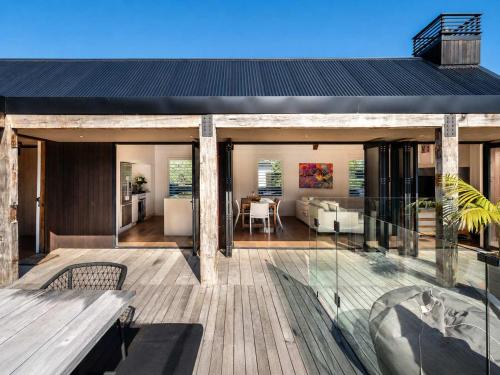 a house with a deck with a view of a living room at Blackpool Boathouse - Stay Waiheke in Oneroa