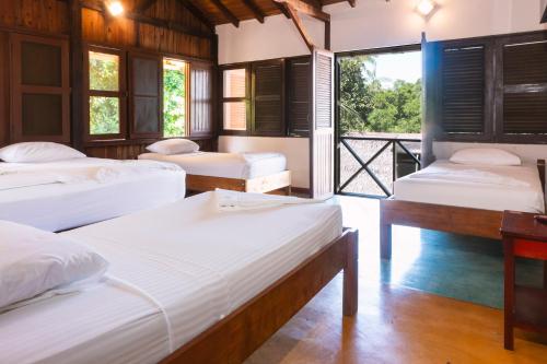 a room with four beds and a desk and windows at Waira Selva Hotel in Puerto Nariño