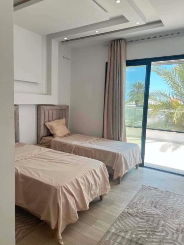 a bedroom with two beds and a large window at Dar sirine in Arkou