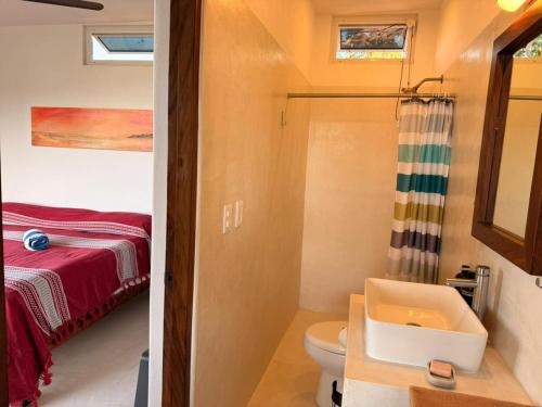 a bathroom with a sink and a toilet and a bed at Casa Maracuyá Chacala in Chacala