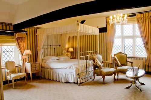 a bedroom with a canopy bed and two chairs at Albright Hussey Manor in Shrewsbury