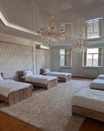 a large room with three beds and chandeliers at Aigul Hostel in Shymkent