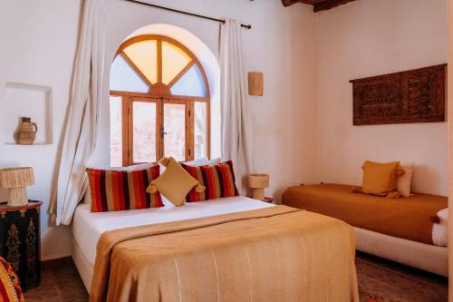 a bedroom with two beds and a window at Riad Eucalyptus, hôtel de charme Essaouira in Essaouira