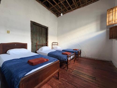 a room with three beds and a wooden floor at Casa Beco do Sertão - Praça do Coreto in Goiás