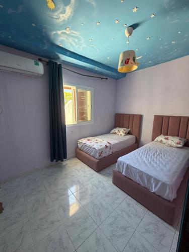 a bedroom with two beds and a blue ceiling at Boustan homes in Cabo Negro