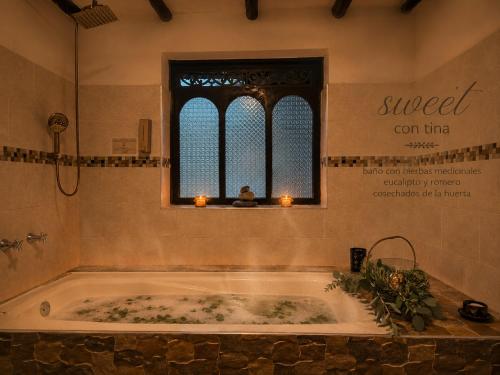 a bath tub in a bathroom with a window and candles at Hotel Pueblo Dorado Sesquilé in Sesquilé