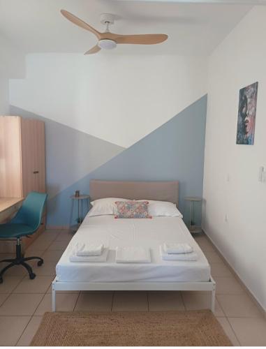 a bedroom with a white bed and a chair at Maria's Studio No3 in Heraklion in Thérissos