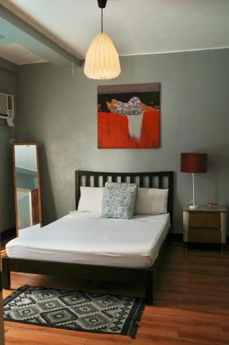 a bedroom with a white bed with a painting on the wall at Apartment with Kitchen Walking Distance to Station Two in Boracay