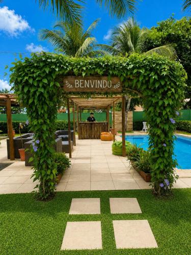 an ivy covered entrance to a resort with a pool at Alisios Kite Lodge in Cumbuco