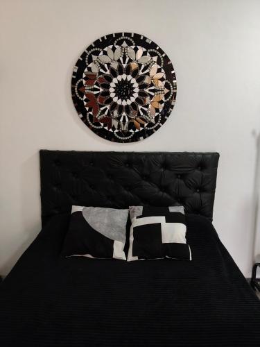 a black bed with a black headboard and a plate on the wall at 3 Acogedor y confortable monoambiente in Santiago del Estero
