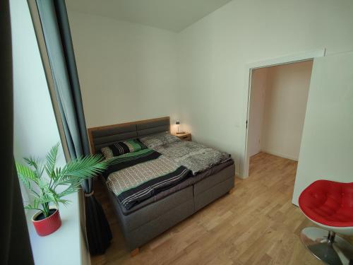 a small bedroom with a bed and a red chair at Apartment Sarah LIL SIS in Tulln
