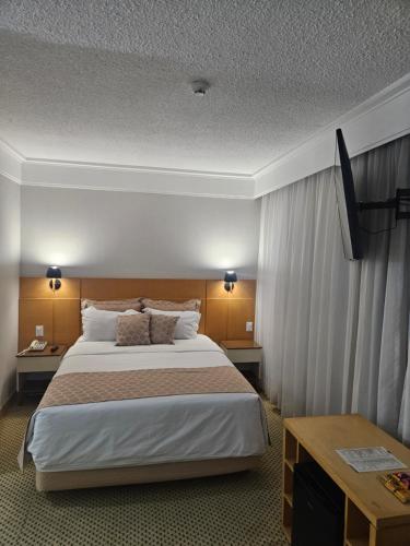a hotel room with a large bed and a table at Flat Hotel Guarulhos SL Aeroporto GRU in Guarulhos