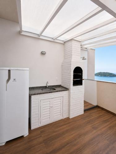 a kitchen with a white refrigerator and an oven at Porto Real Resort Suítes in Mangaratiba
