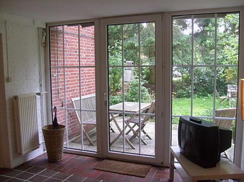 eine abgeschirmte Veranda mit einem TV und einem Tisch in der Unterkunft Ferienwohnung in Hamburg West in Hamburg