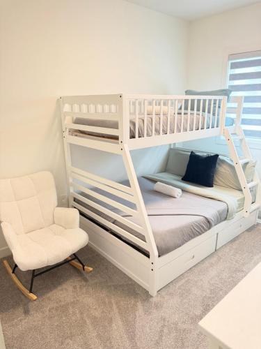 a white bunk bed and a chair in a room at Emerald - 10mins from Stampede Park in Calgary
